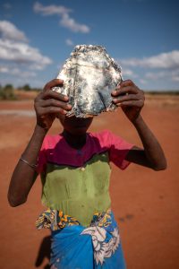 July 27, 2025 | Benato Atsimo, Betroka District, Anosy Region, Madagascar
In the photo, 15-year-old Nekeny holds a sheet of mica in front of her face. Once a child laborer in the mica mines, she didn’t know there was any other way. “I didn’t know it was wrong. I thought it was just life,” she says. The sheet of mica hiding her face speaks to a past that often kept children like her invisible.
Now enrolled at one of the three public primary schools established through the FAMAHA 2 project—supported by Terre des Hommes Netherlands—Nekeny is reclaiming her future. She dreams of becoming a teacher “so that other children can learn early what I learned late.”